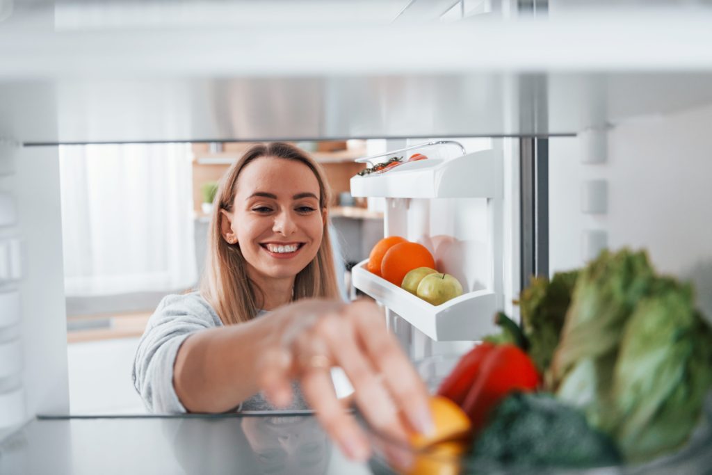 happy-woman-taking-vegetable-from-the-fridge