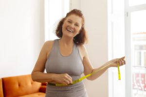 happy-senior-woman-measuring-her-waist-with-tape-