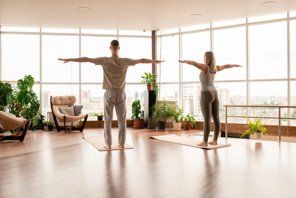 back-view-of-young-active-couple-standing-on-mats